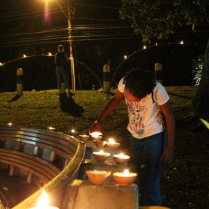 A young girl lights a deya during Divali