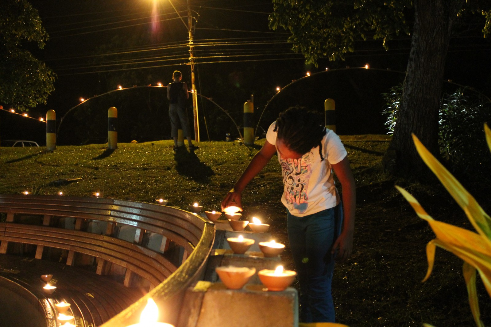 A young girl lights a deya during Divali